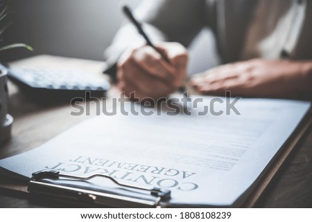 Hand holding pen signing contract in important documents.