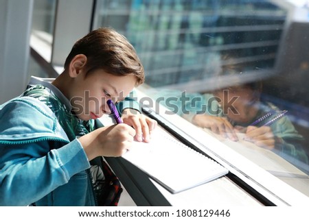 Child writes in notebook at the airport