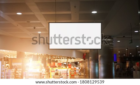 white blank poster with mockup space hangs on chain from ceiling in supermarket or city mall inside