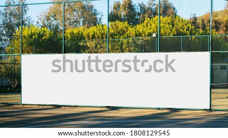large blank white poster with mockup space hanging on metal fence of play ground outside