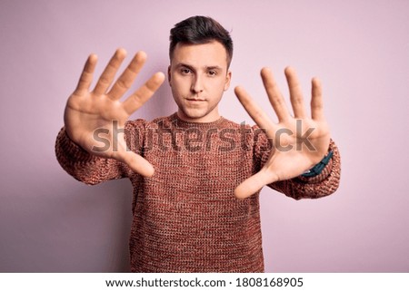 Young handsome caucasian man wearing casual winter sweater over pink isolated background doing frame using hands palms and fingers, camera perspective