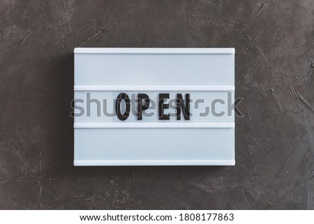 Signboard OPEN of lightbox on black wall concrete background.