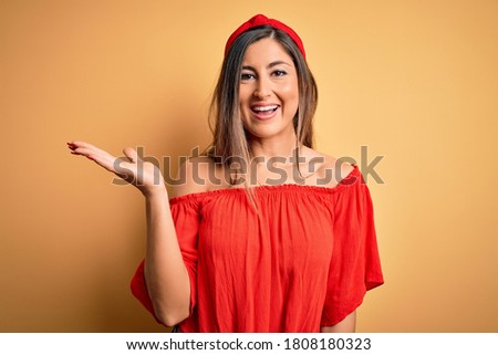 Young beautiful woman colorful summer style over yellow isolated background smiling cheerful presenting and pointing with palm of hand looking at the camera.
