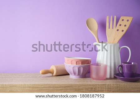 Kitchen utensils and dishware on wooden shelf. Kitchen interior purple background  Royalty-Free Stock Photo #1808187952