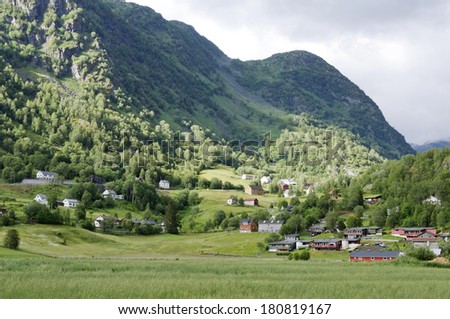 Village on a hillside. Farmland and forests. Some rays of sunshine. Buildings in the valley.