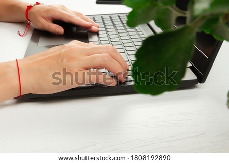 female hands are typing text on laptop keyboard on white wooden table background