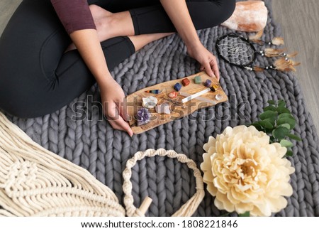 chakra meditation healing macrame chunky knit blanket with woman holding wooden tray of healing stones Royalty-Free Stock Photo #1808221846
