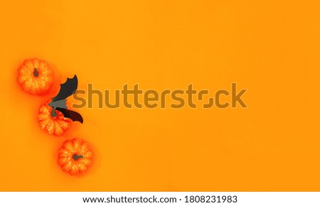 Halloween flat lay with pumpkins, spiders and bat on the yellow orange background. Autumn holiday season.