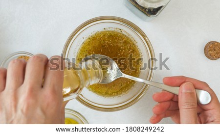 Salad dressing ingredients, as olive oil, honey, lemon juice, seasoning, mustard and black pepper. Honey mustard salad dressing for lettuce salad recipe Royalty-Free Stock Photo #1808249242