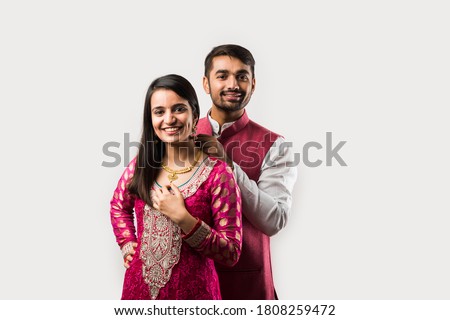 Indian man tying or presenting gold necklace to his beautiful wife on birthday, valentine's day, anniversary or Diwali festival