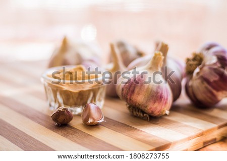 Beautiful and large garlic lies with garlic seasoning on a brown wooden board.
