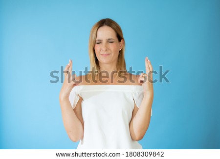 Beautiful woman in white shirt with fingers crossed gesture
