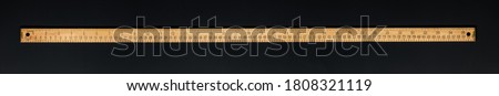 Wooden yardstick on black backgrounds whit centimeters and inches fractions scales. Royalty-Free Stock Photo #1808321119