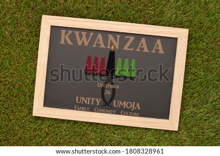 Kwanzaa Umoja (African for Unity ) Kinara (Candle Holder) Blackboard on green turf grass