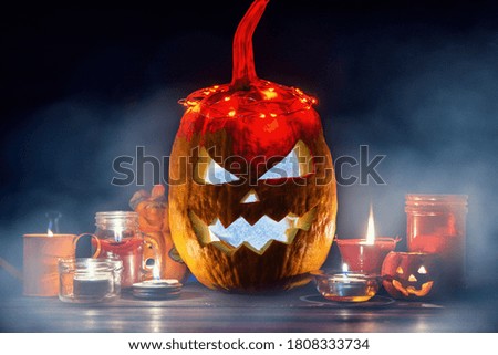 Halloween Jack o Lantern pumpkin on a black background in the fog. around candles, spiders, halloween Trick or Treat decor
