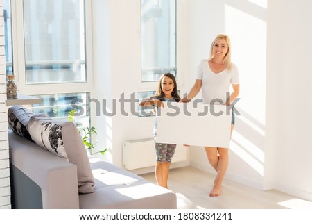 mother and daughter hangs a large photo canvas at home
