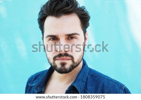Vertical portrait of mature handome fit man sitting outside over blue background stock photo.