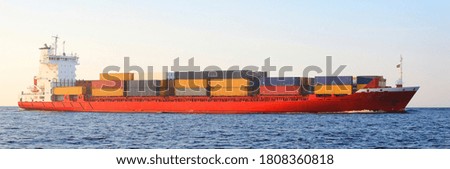 Large cargo container ship arriving to the harbor at sunset, close-up. Freight transportation, global communications, logistics, industry, environmental damage, graphic resources. Panoramic view