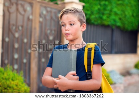 Pupil boy with book and backpack outdoor. Back to school