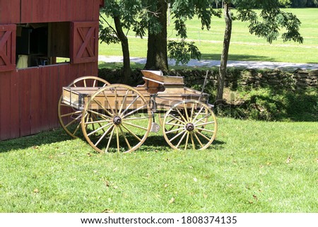 An antique wooden horse cart is parked in front of a barn Royalty-Free Stock Photo #1808374135
