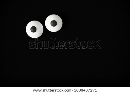 Halloween background, pair of white bulged eyes in the dark, black background, copy space.