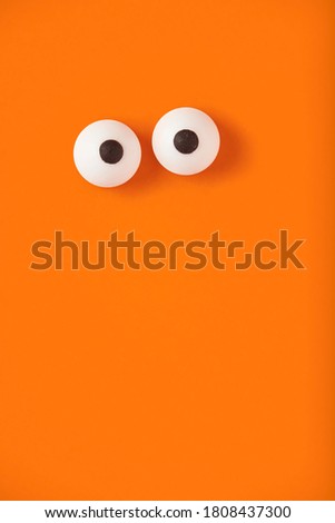 Halloween background, pair of eyes on orange, copy space.