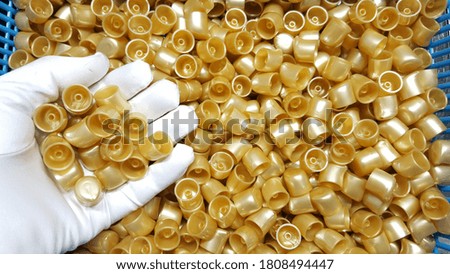 White gloves handle plastic workpiece and gold color cosmetic, in plastics industry