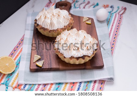 Lemon Pie portions meringue toasted on wooden board on kitchen rag