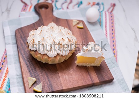 Lemon Pie portions meringue toasted on wooden board on kitchen rag