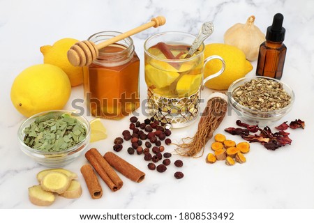 Natural medicinal herbal remedy for cold & flu virus with hot drink with fresh ginger, lemon, honey, cinnamon. echinacea, hawthorn berries, ginseng & eucalyptus essential oil. Immune boosting. Royalty-Free Stock Photo #1808533492
