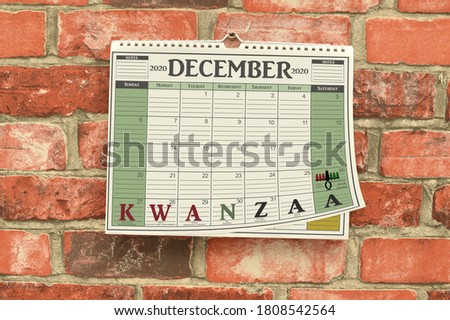 Kwanzaa December 2020 Calendar Page lifted up hanging on brick wall