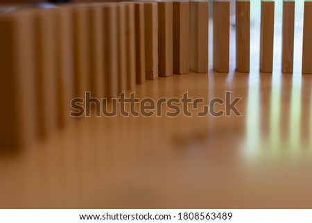 Wooden block domino standing stable on wood table, business chain and connection symbol, domino effect theory