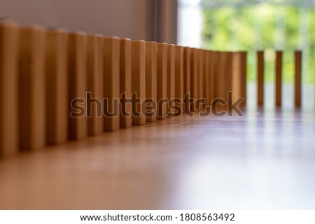 Wooden block domino standing stable on wood table, business chain and connection symbol, domino effect theory