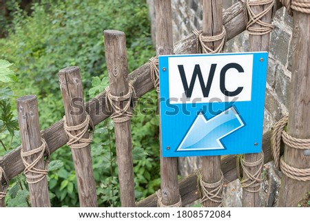 Signboard for WC hanging on wooden fence for toursits.  