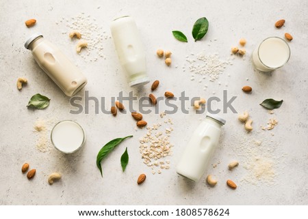Vegan plant based milk and ingredients, top view, copy space. Various dairy free, lactose free nut and grains milk, substitute drink, healthy eating. Royalty-Free Stock Photo #1808578624