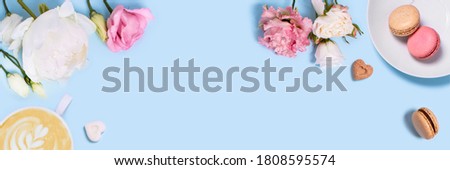 Blue background with flowers, macaroons, and a Cup of coffee. Top view with space for your text.