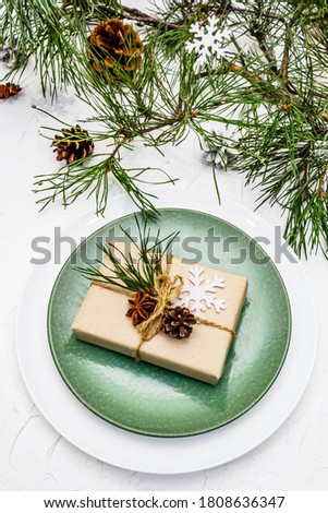 Christmas or New Year table setting. Festive cutlery, ceramic plates with fresh pine branch, cones, zero waste gifts and star anise. White putty background, close up
