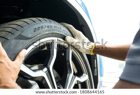 Selective focus of  Tire Size numbers and Tyre Load Indexes on the sidewall on blurred hand of Auto mechanic on background. Royalty-Free Stock Photo #1808644165