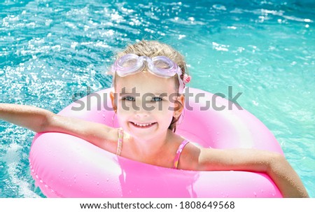 Cute smiling little girl child in swimming pool outdoor