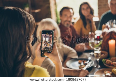 Photo of full family gathering small daughter hold telephone make adorable picture digital camera focusing push button dinner big table turkey generation in home evening living room indoors