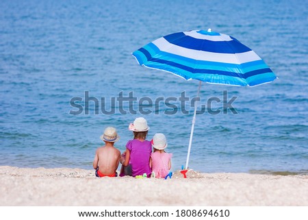 Happy children playing by the sea with umbrella background