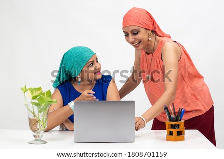 Two smiling Indian women at the table, distance learning for students. Freelancer, distant work, work at home, online education, Discussing project.
