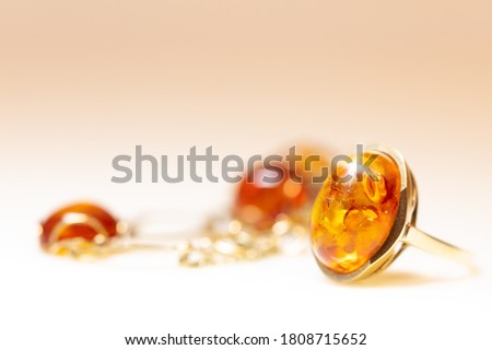 Amber jewelry like necklace, bracelet and ring with noble metal like gold. warm white background with copyspace Royalty-Free Stock Photo #1808715652