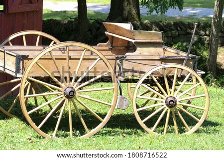 An old wooden buckboard wagon is parked on the grass.