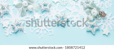 Christmas decoration on the pastel blue background. Paper snowflakes and silver stars. New year greeting card template. Holiday mock up. Minimal stylish luxury tender style. Banner, copy space