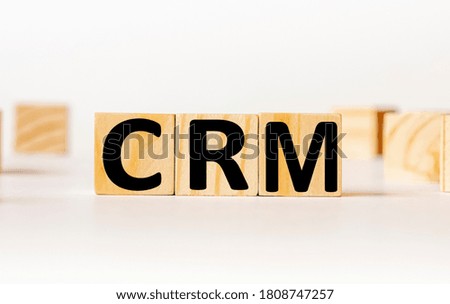 A wooden block with the word CRM Customer relationship management written on it on a white background. Business concept