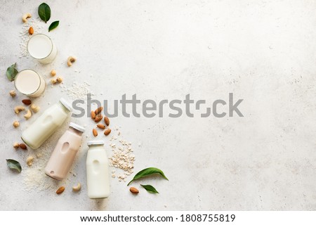 Vegan plant based milk and ingredients, top view, copy space. Various dairy free, lactose free nut and grains milk, substitute drink, healthy eating. Royalty-Free Stock Photo #1808755819