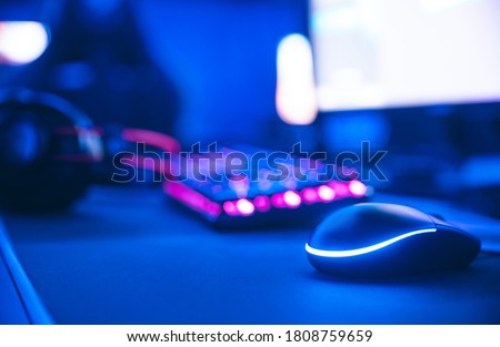 Computer gamer workplace for new game mouse and keyboard with blur pink neon light background.