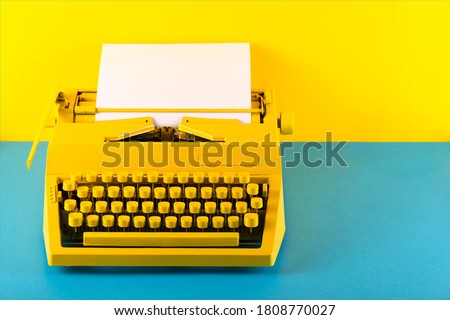 Yellow bright typewriter on a yellow and blue background. Symbol for writing, blogging, new ideas and creativity. Copy space Royalty-Free Stock Photo #1808770027