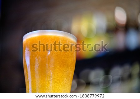 Close up of craft beer poured into a pint glass on bar counter. Tap beer in a pub background. Cold light beer with copy space.  Shallow DOF.